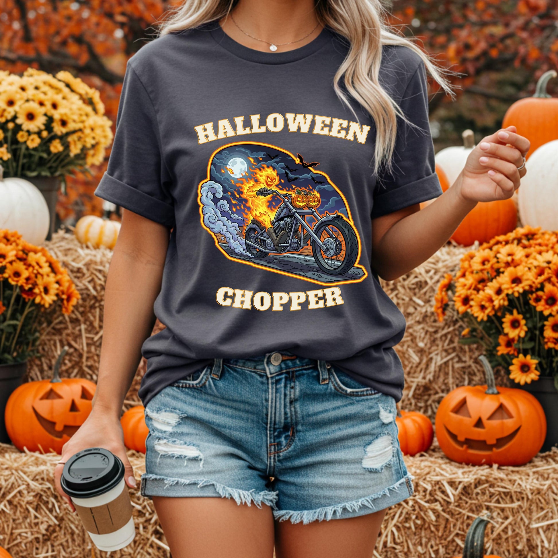 A woman wearing a t-shirt with a graphic of a motorcycle and the text "HALLOWEEN CHOPPER" is standing in front of a Halloween-themed display with pumpkins and flowers.