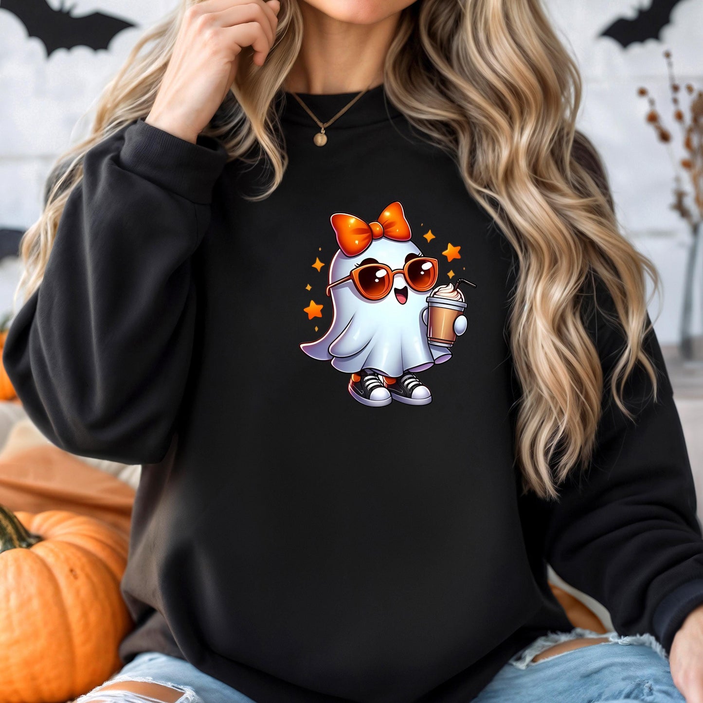 A woman wearing a black sweatshirt with a cartoon ghost character on it, holding a drink and wearing sunglasses.