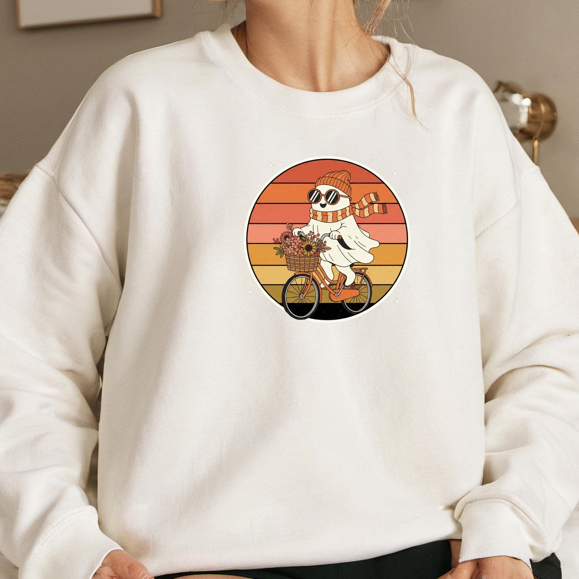 A white sweatshirt with a graphic design depicting a ghost riding a bicycle.
