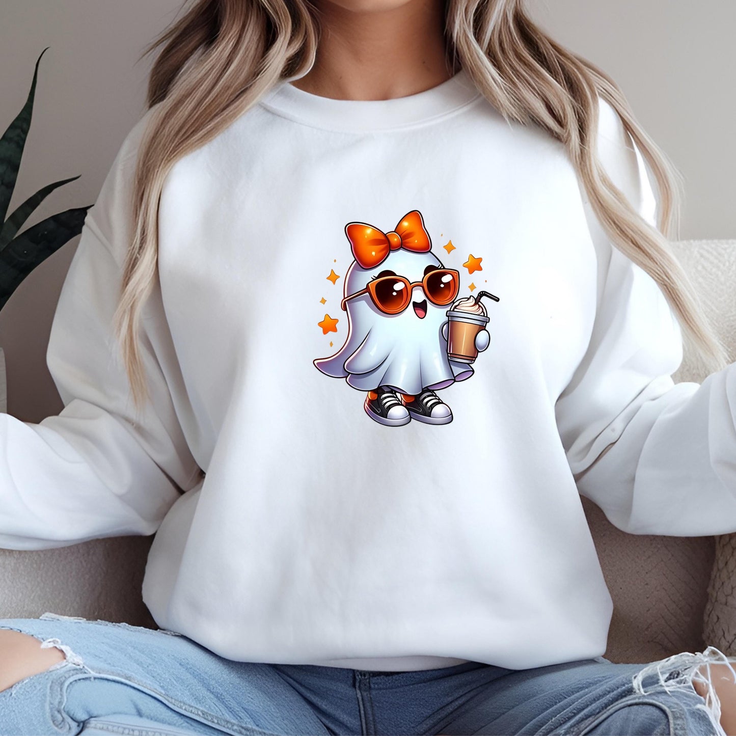 A woman wearing a white sweater with a cartoon ghost character on it, holding a drink and wearing sunglasses.