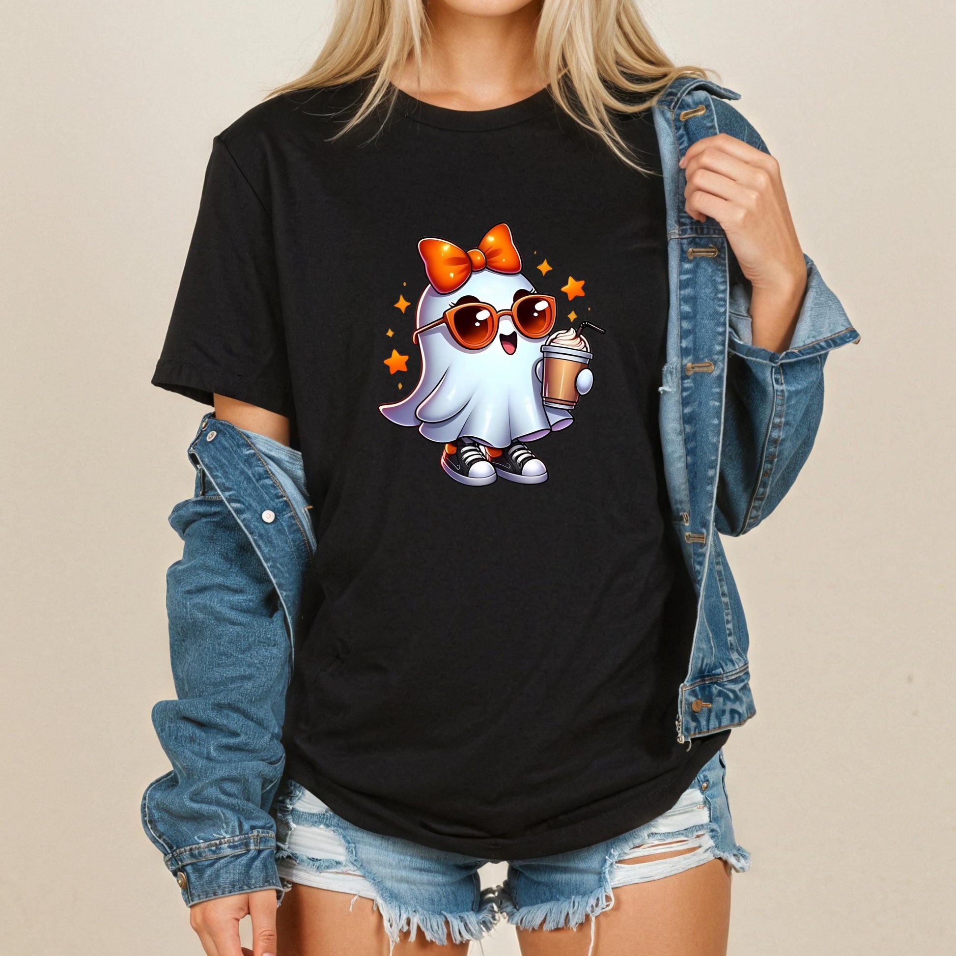 A woman wearing a black t-shirt with a graphic of a ghost character and sunglasses, paired with denim shorts and a denim jacket.