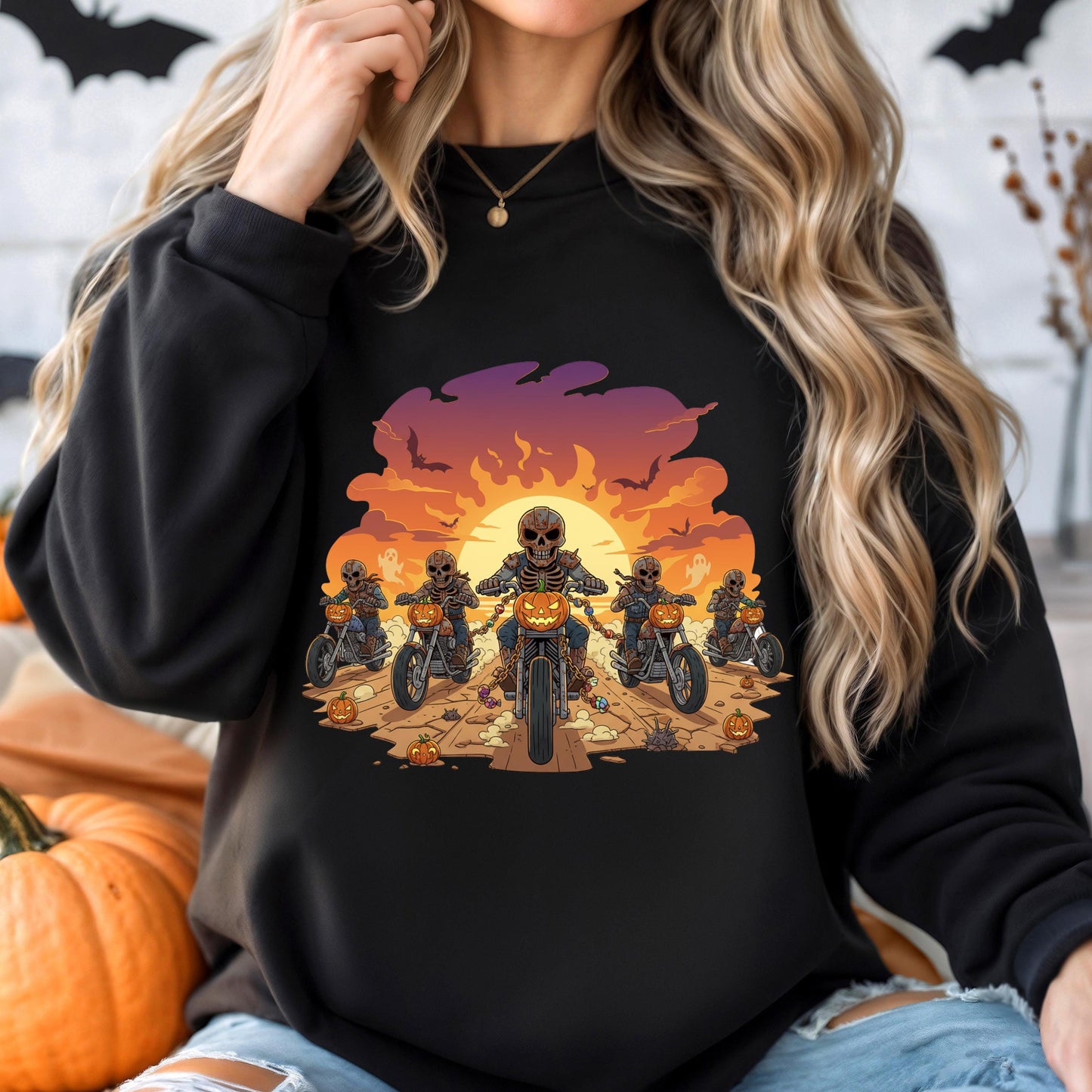 A woman wearing a black sweatshirt with a graphic design depicting a group of people riding motorcycles against a sunset background.