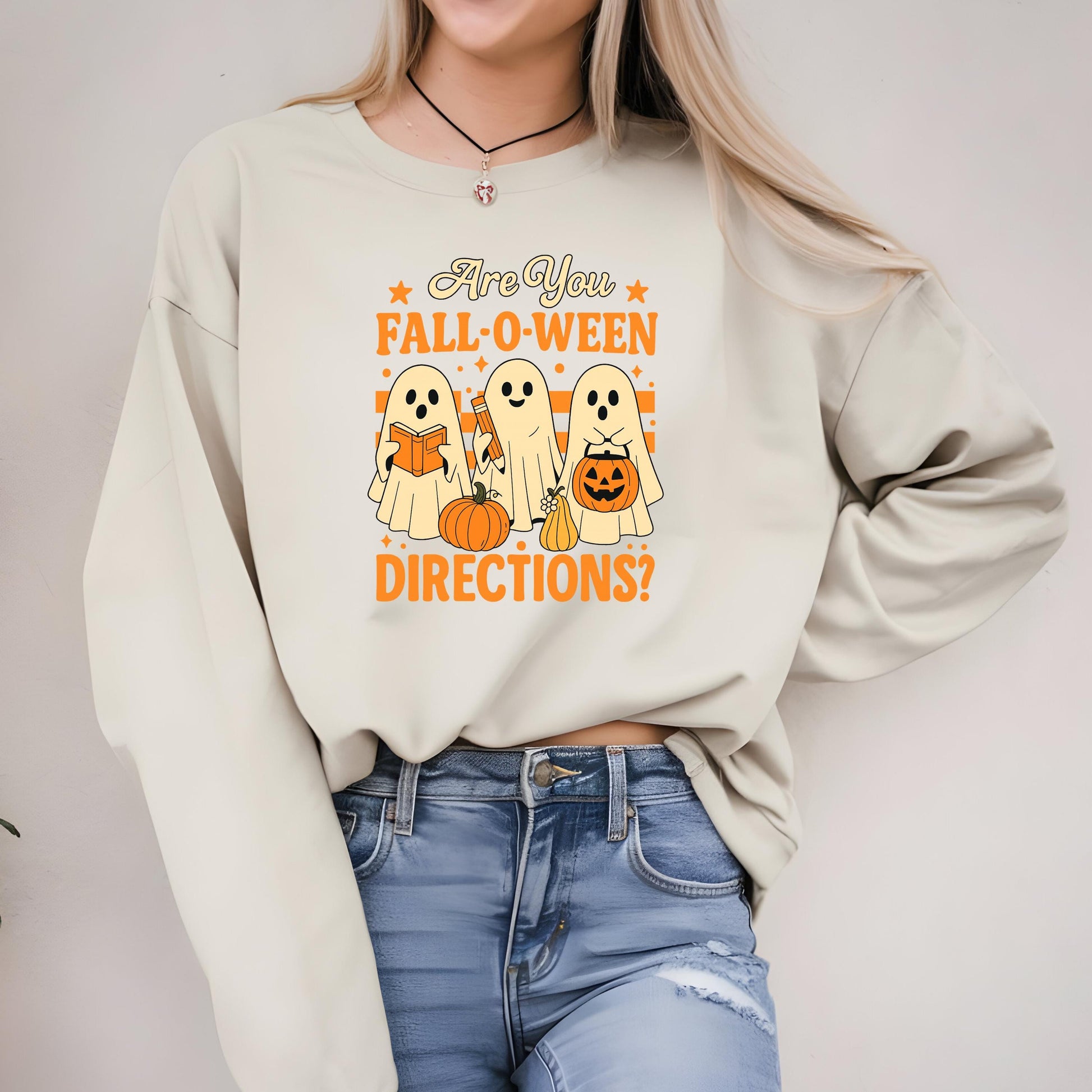 A woman wearing a white sweatshirt with a Halloween-themed graphic design.