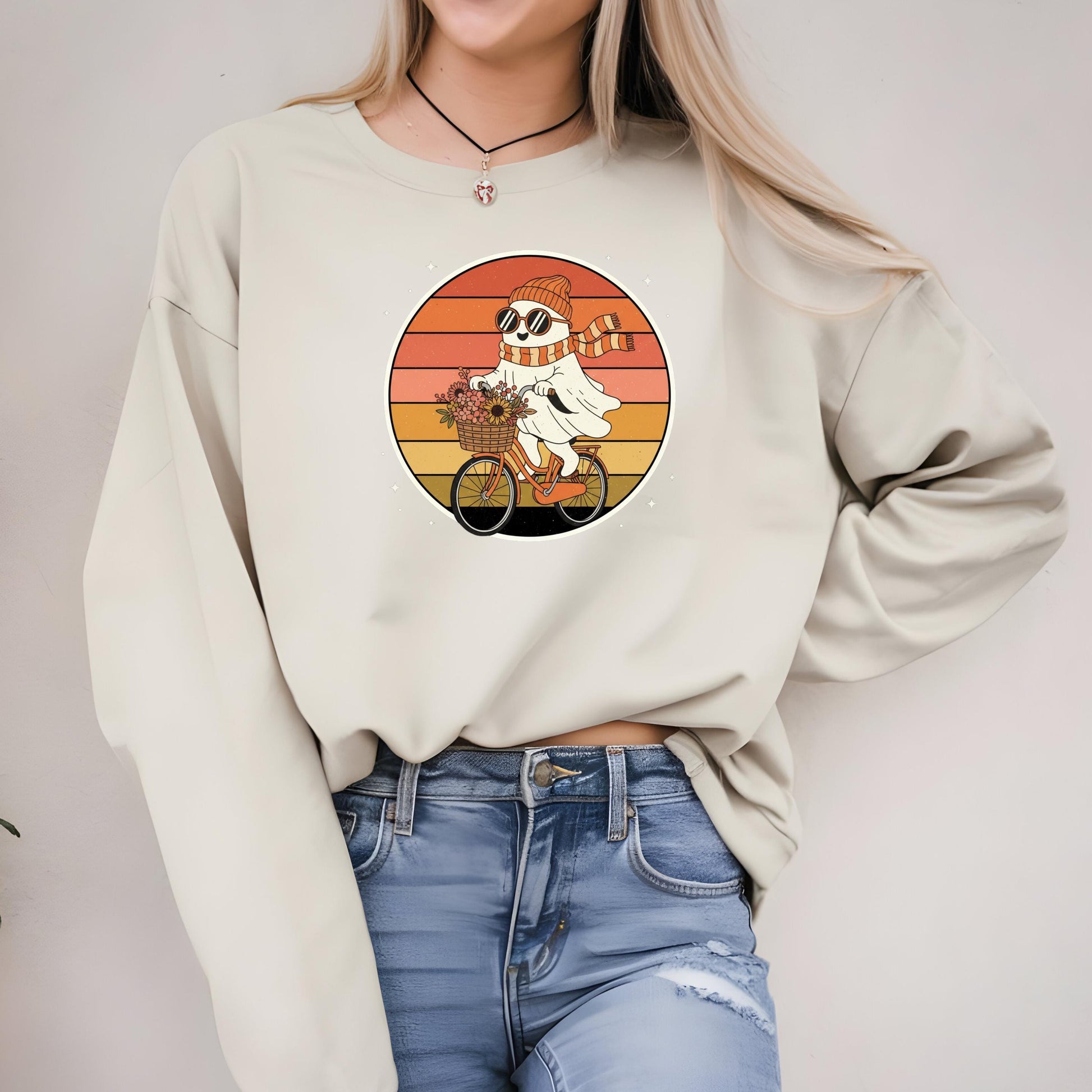 A woman wearing a white sweater with a graphic of a ghost riding a bicycle.