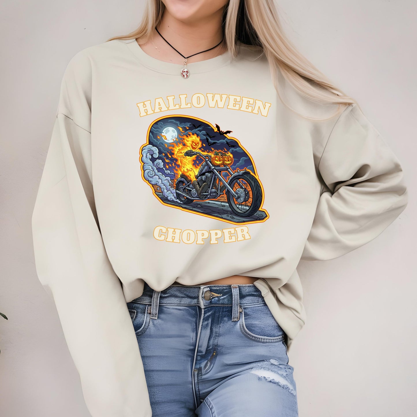A woman wearing a white sweater with a Halloween-themed graphic of a motorcycle and a ghost on it.