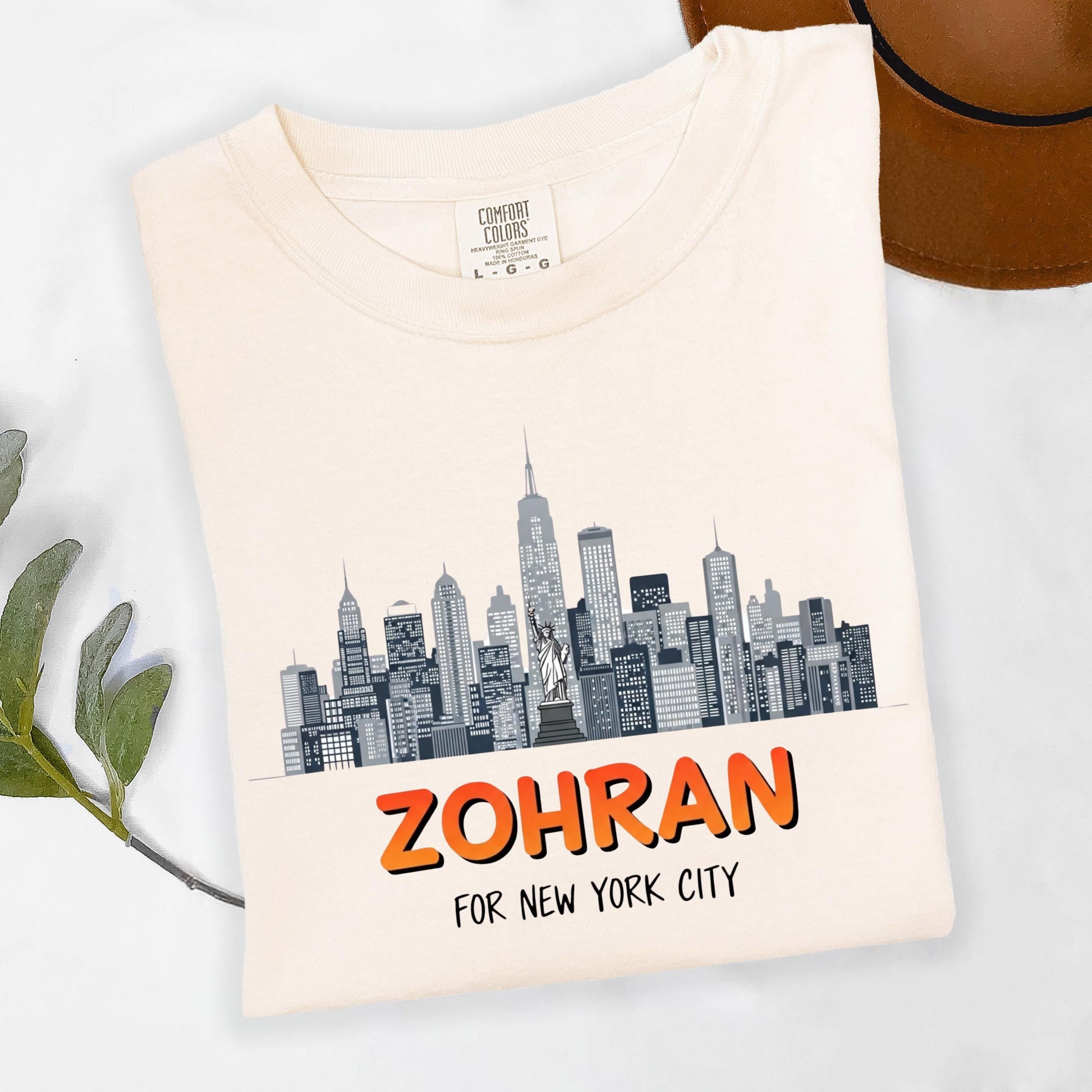 A white t-shirt with a graphic design of a city skyline and the text "ZOHRAN FOR NEW YORK CITY" printed on it.