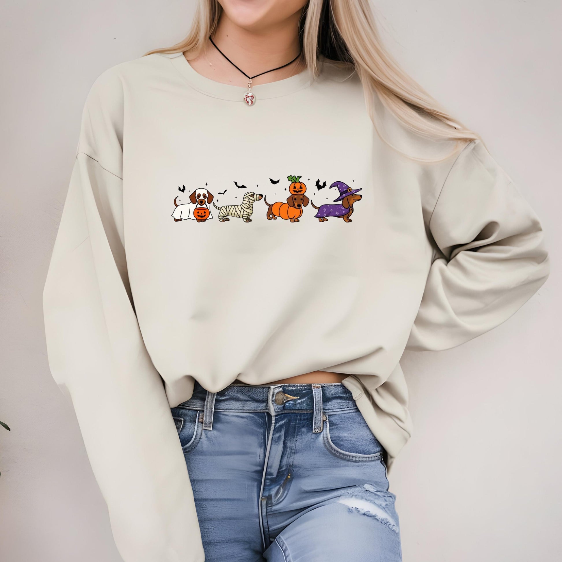 A woman wearing a white sweater with a graphic of cartoon dogs in Halloween costumes.