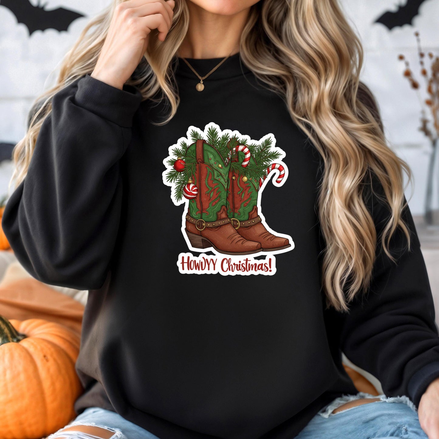 A woman wearing a black sweatshirt with a graphic of a cowboy boot and Christmas decorations.