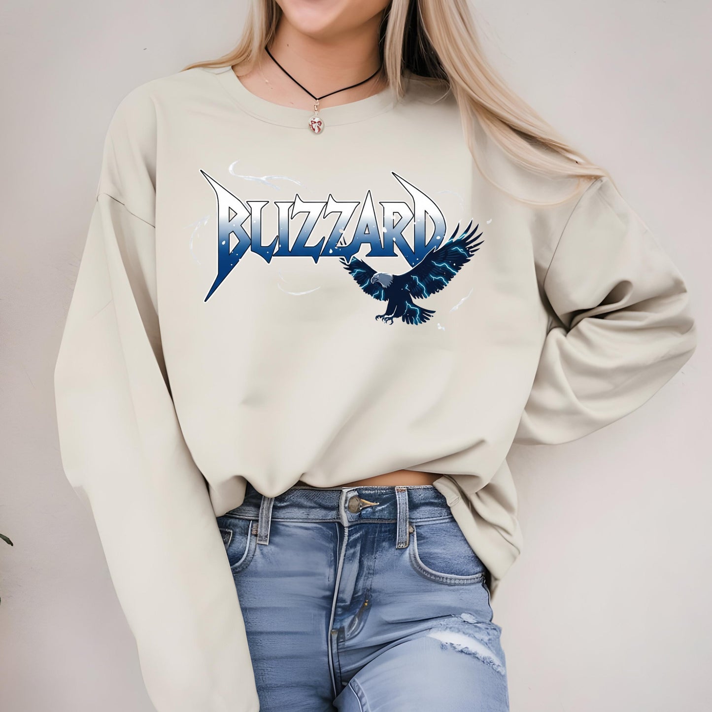 A woman wearing a white sweatshirt with a graphic design of a blue bird and the word &quot;BLIZZARD&quot; printed on it.