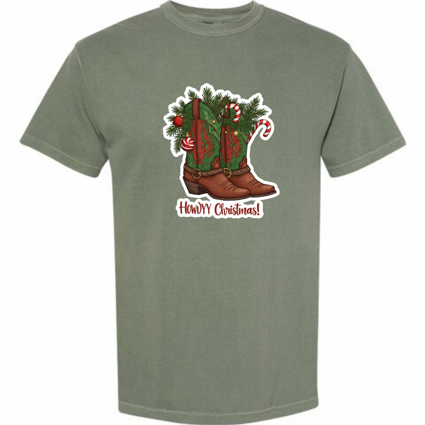 A t-shirt with a graphic design depicting a pair of brown cowboy boots adorned with Christmas decorations, including candy canes and pine branches. The text &quot;Howdy Christmas!&quot; is displayed below the boots.