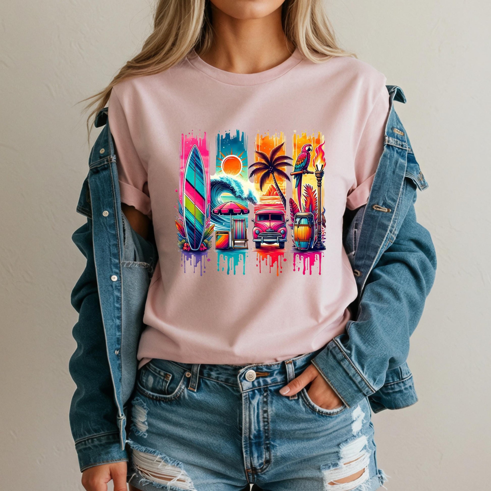 A woman wearing a pink t-shirt with a colorful graphic design featuring a surfboard, palm tree, and other beach-related elements.