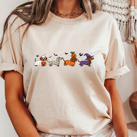 A woman wearing a white t-shirt with a graphic design of five cartoon dogs dressed in Halloween costumes.
