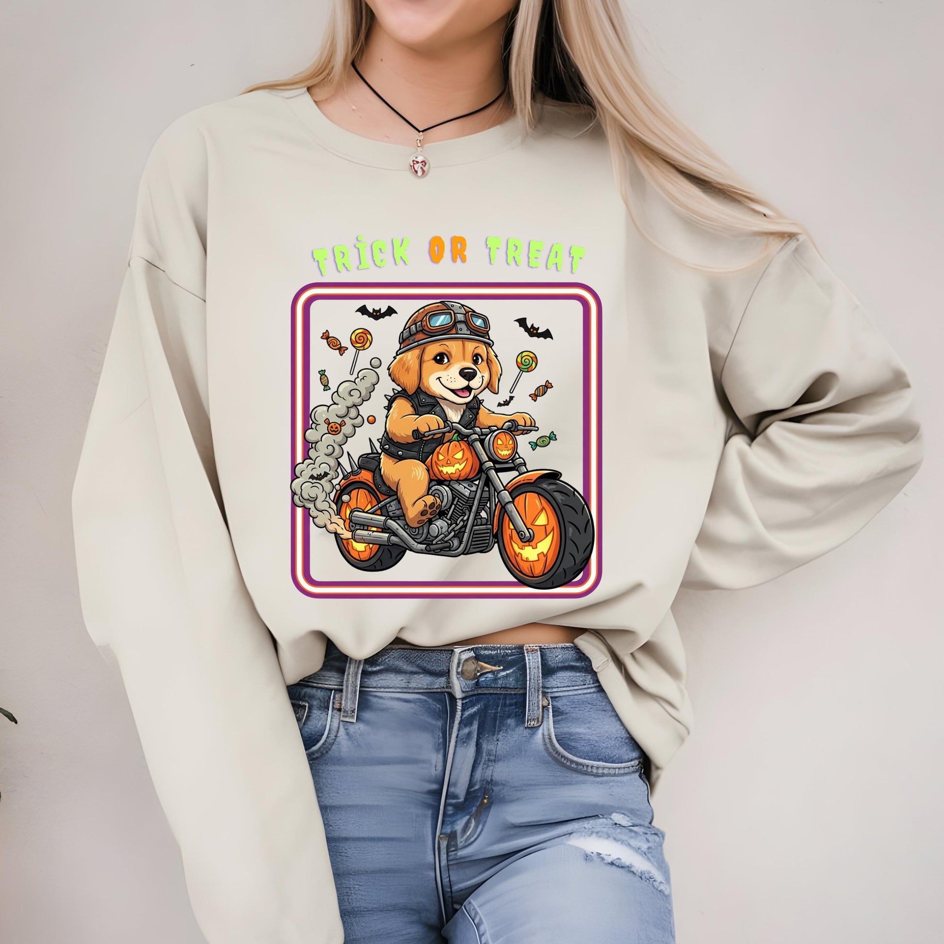 A woman wearing a white sweater with a graphic design of a dog riding a motorcycle, surrounded by Halloween-themed elements such as bats, pumpkins, and candy canes.