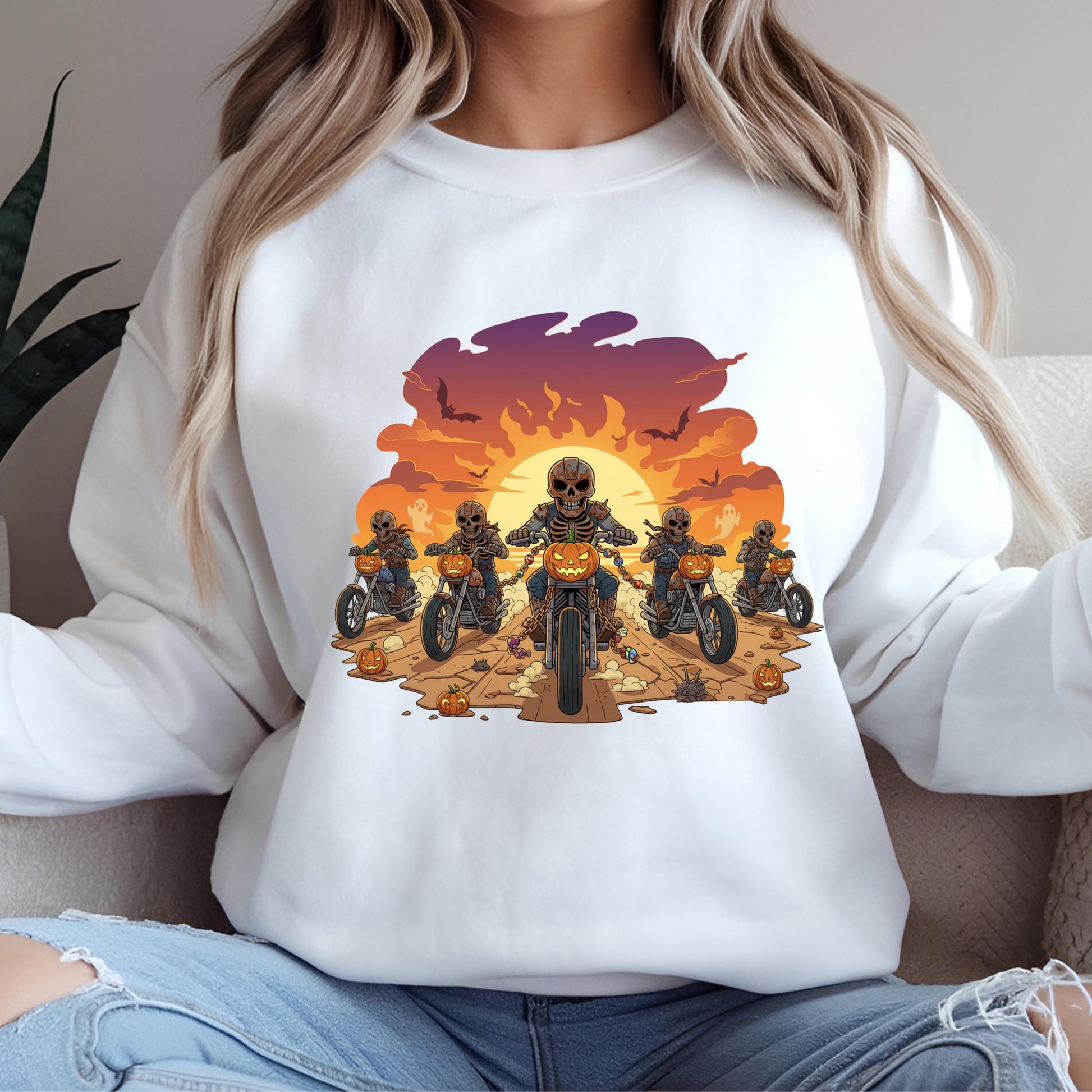 A white sweatshirt with a graphic design depicting a group of people riding motorcycles against a sunset background.