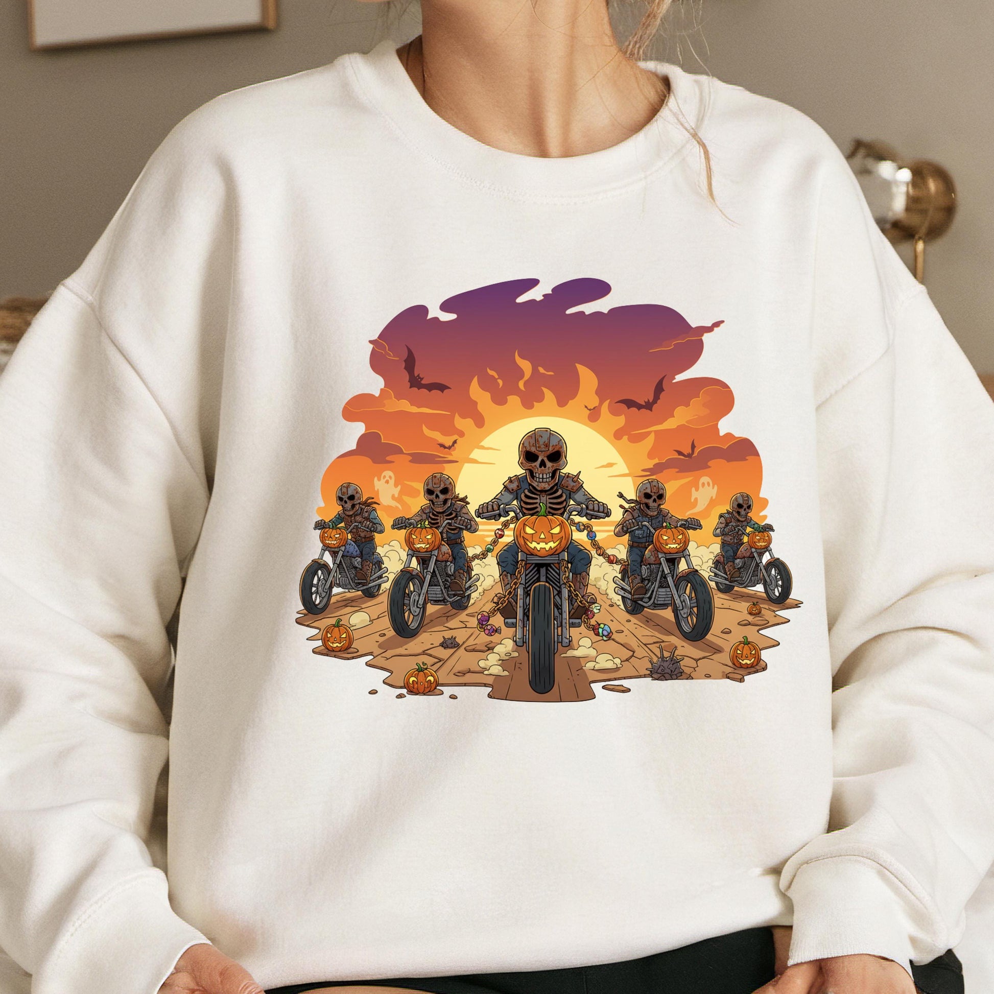 A white sweatshirt with a graphic design depicting a group of skeletons riding motorcycles against a sunset background.