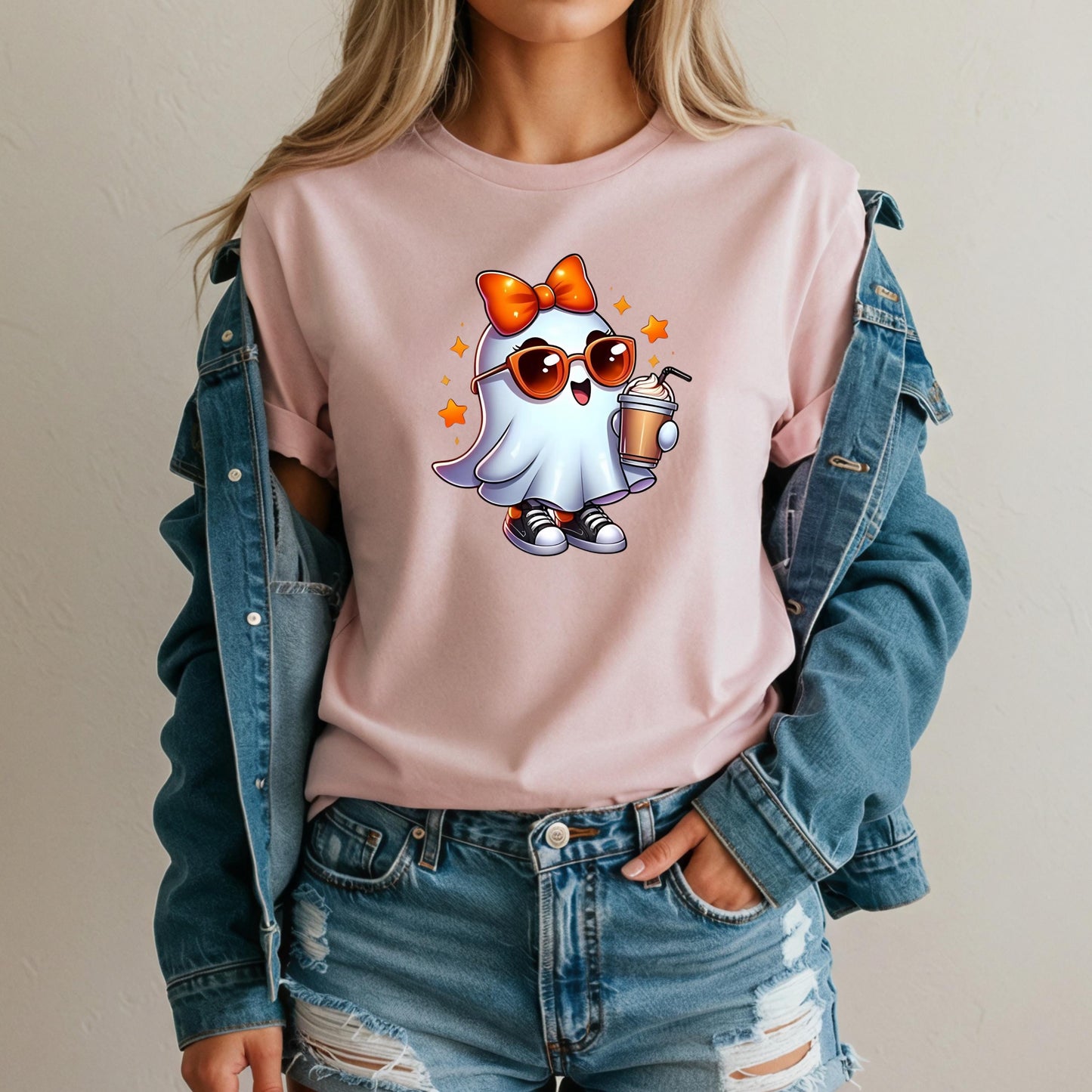 A woman wearing a pink t-shirt with a cartoon ghost character and sunglasses, paired with a denim jacket and distressed jeans.