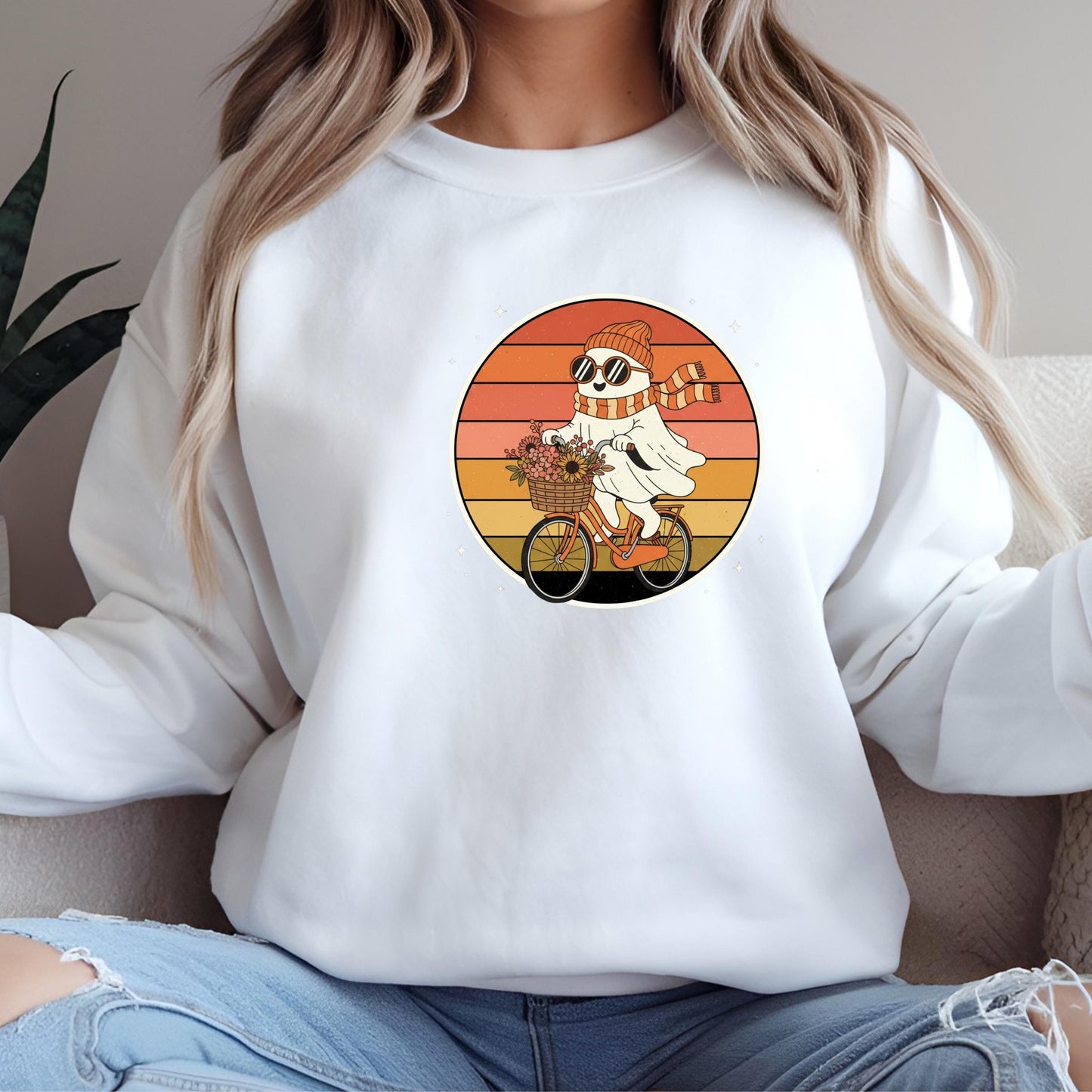 A woman wearing a white sweatshirt with a graphic of a ghost riding a bicycle.